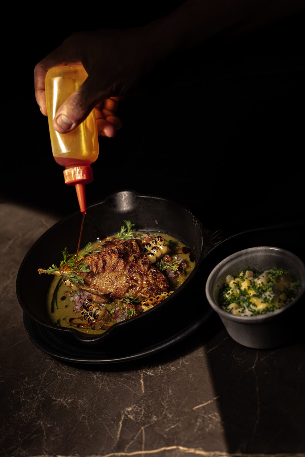 PIEDRA — a hand saucing a plate on dark stone